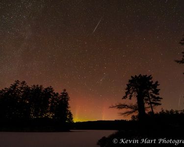 "Silence Under a Dancing Sky" - The Aurora Borealis and the Geminid Meteor Shower over a frozen Lowell Lake in Londonderry, VT.