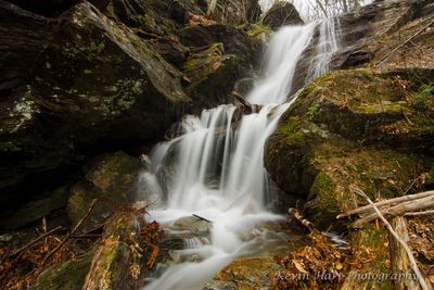 A waterfall in the shape of a chair forms on Mt. Mansfield during the snowmelt. The foliage has not returned yet and the waterfall is framed by fallen leaves and rocks.