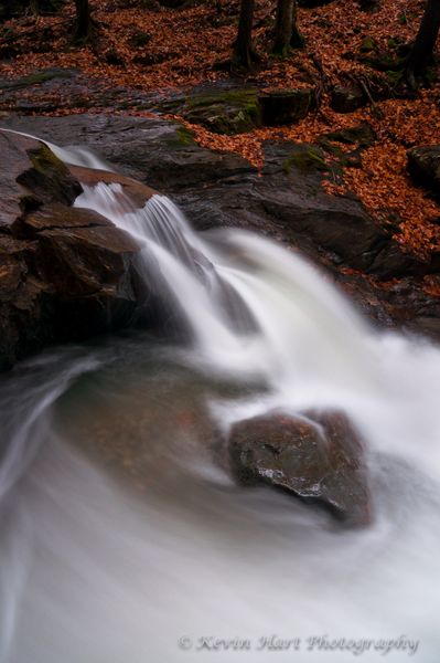 Water shoots off a chute and swirls around a rock in the middle of the eddy in late autumn.