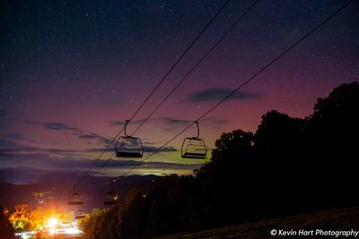 Purple, green, and magenta aurora colors behind a ski mountain chairlift.