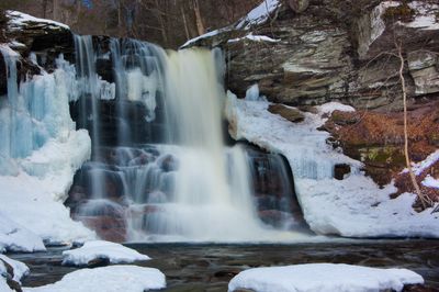 Flowing waterfall surrounded by snow and ice.